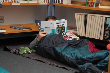 Kind mit Schlafsack und Buch