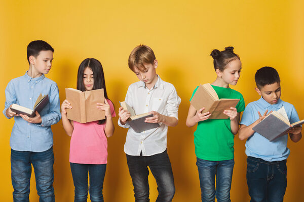 Lesende Kinder vor einer gelben Wand